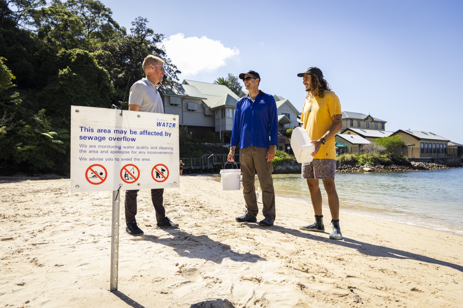 A coastal field team standing beside a water-quality warning sign